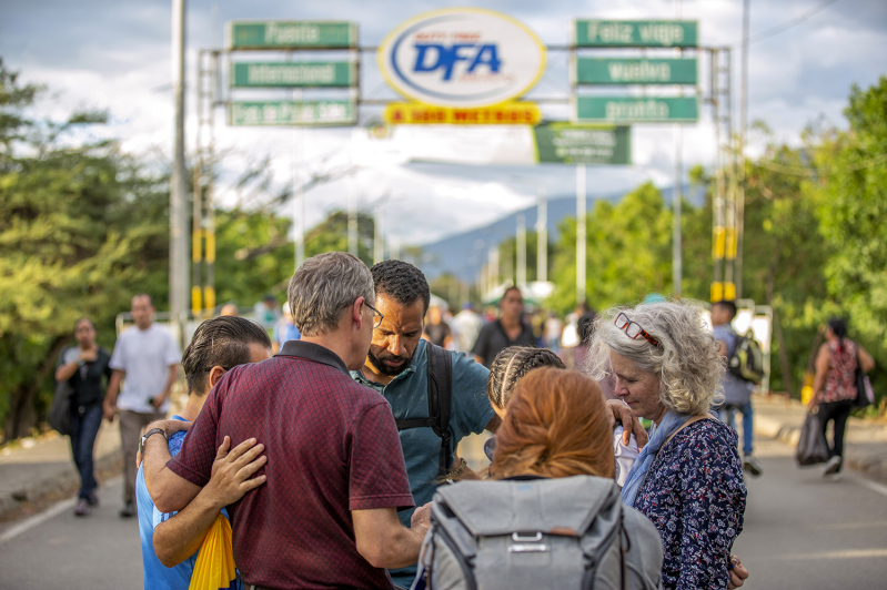 Missionaries and volunteers pray with migrants and refugees.