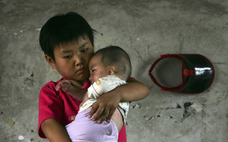 Orphan holding baby orphan in China orphanage