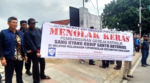 Muslim residents with banner saying they reject construction of Catholic church building in Cipamokolan village, Indonesia.