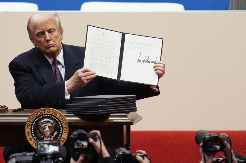 U.S. President Donald Trump holds up an executive order after signing it during an indoor inauguration parade