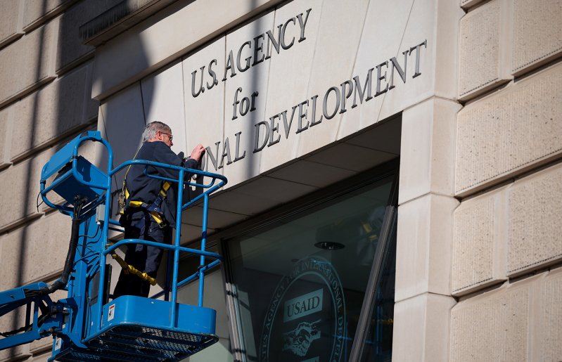 A worker removes the U.S. Agency for International Development sign on their headquarters